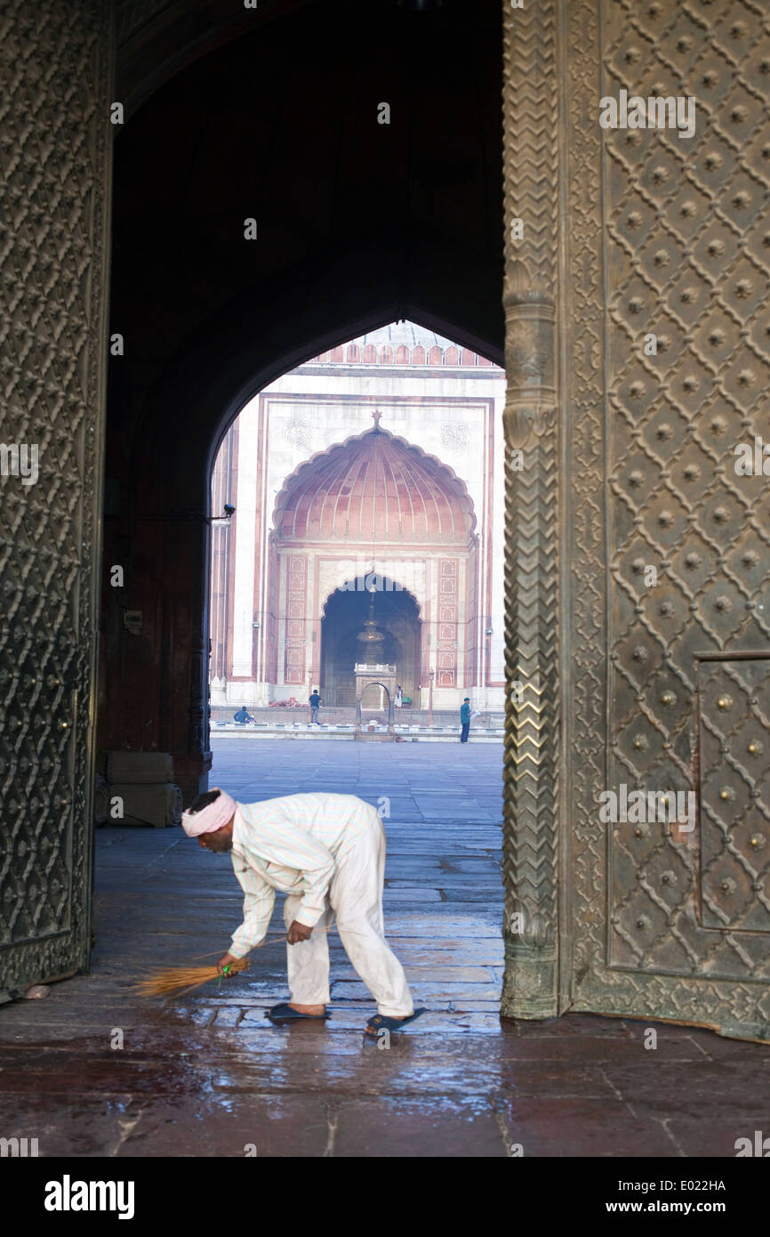 Una escoba limpia los escalones en la parte delantera de la Jama Masjid, Delhi, India Foto de stock