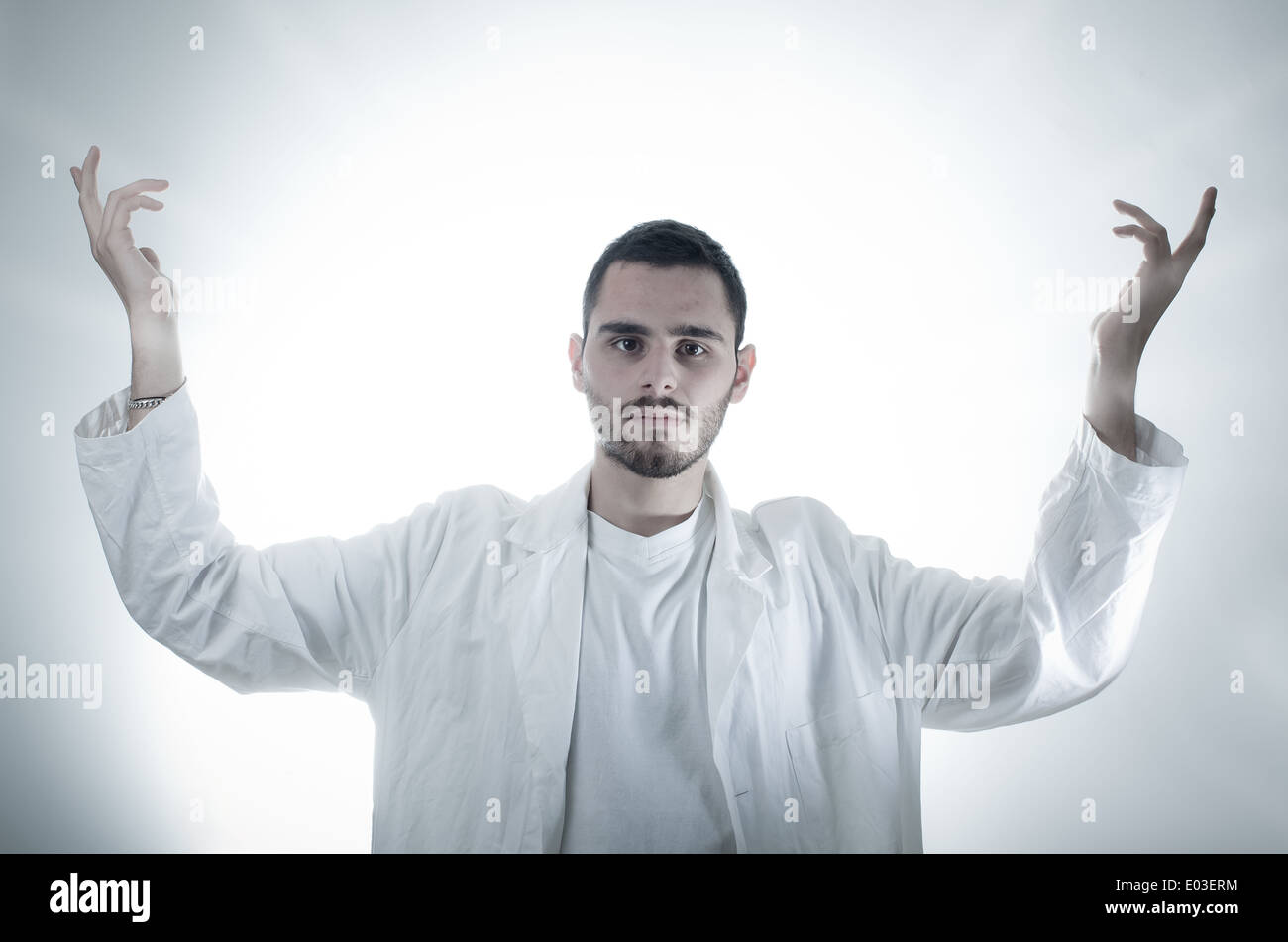 Un joven, Todo-poderoso investigador/estudiante/doctor vistiendo una bata blanca sobre un fondo blanco. Foto de stock