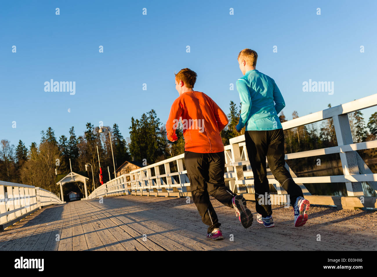 Dos mujeres correr juntos a lo largo del puente al amanecer. Foto de stock