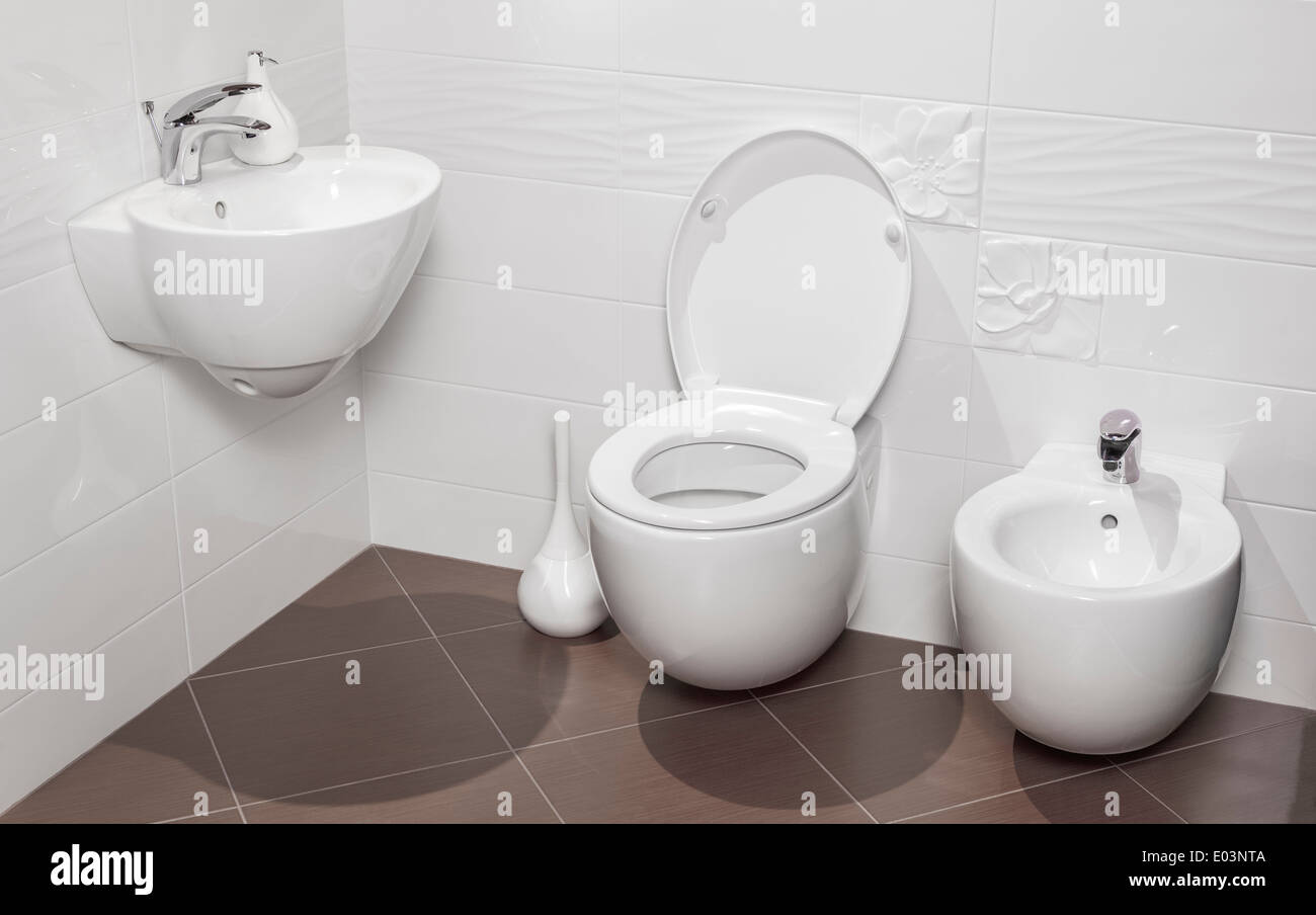 Detalle de un moderno cuarto de baño lujoso con wc, lavabo y bidet, azulejos de color marrón y blanco Foto de stock