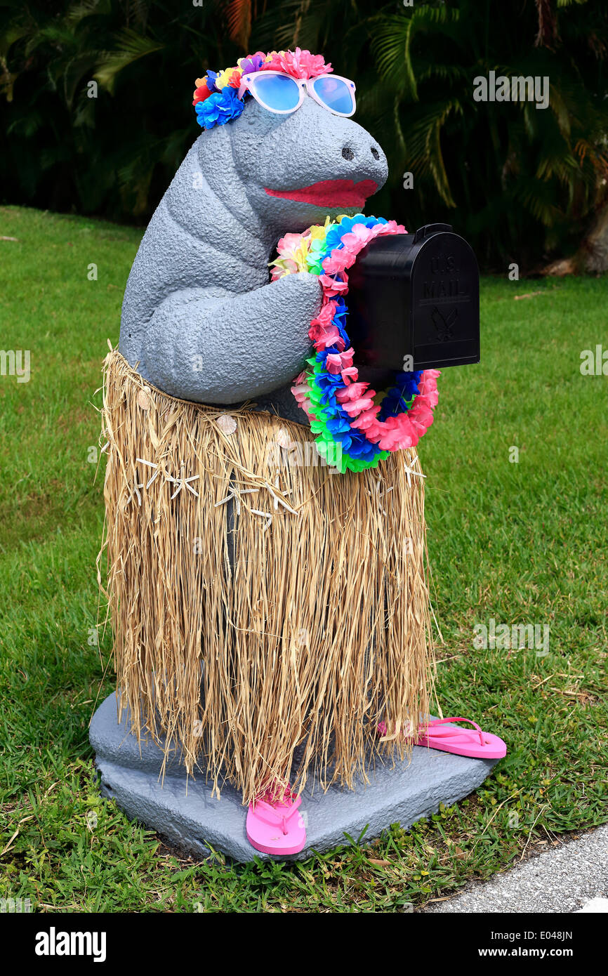 Una casilla de correo puesto en la forma de un manatí con una falda de hierba chancletas y laie Foto de stock
