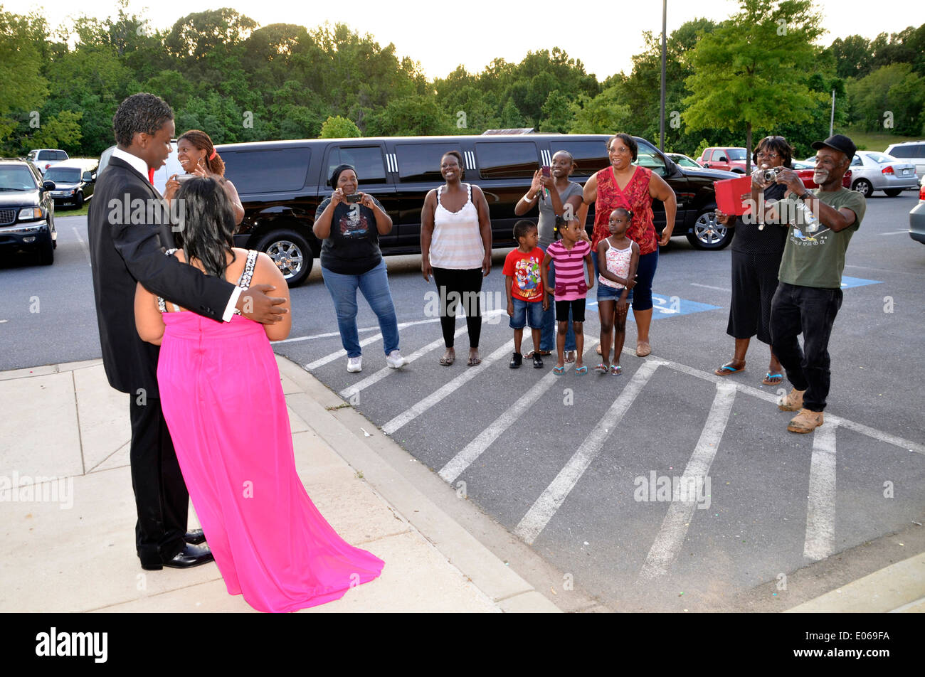 Los familiares se alinean para tomar fotografías de una pareja en su llegada al high school prom. Foto de stock