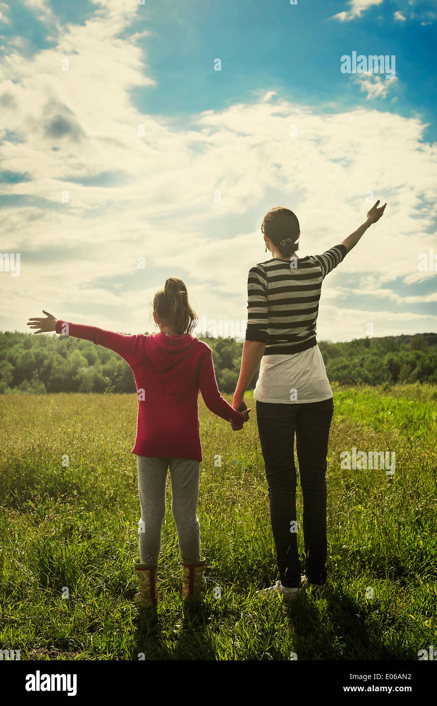 Madre e hija, tirando de sus manos hacia el cielo, los rayos de sol. Foto de stock