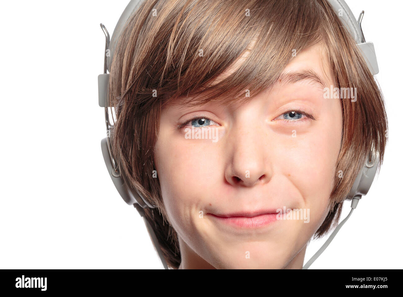 Adolescente masculino con auriculares perjudica la música, aislado en blanco. Foto de stock