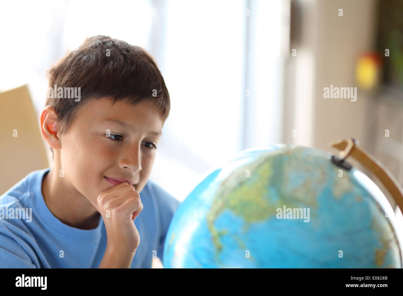 Y0oung boy sueños de viajar como él mira un globo Foto de stock