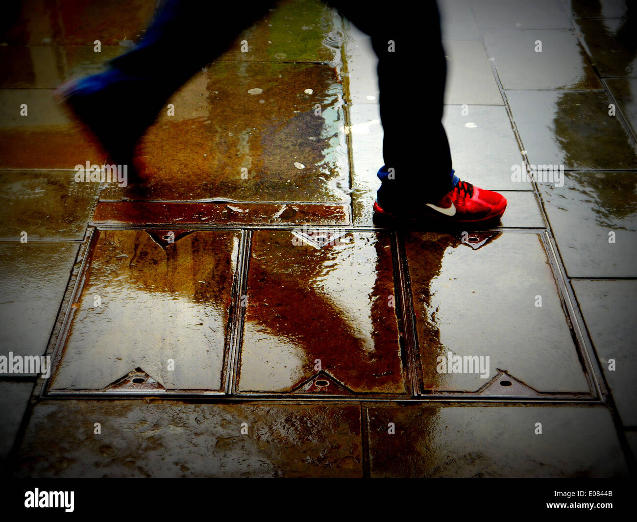 Imagen abstracta de un hombre con zapatillas rojas caminar bajo la lluvia  (sólo piernas y pies mostrando Fotografía de stock - Alamy