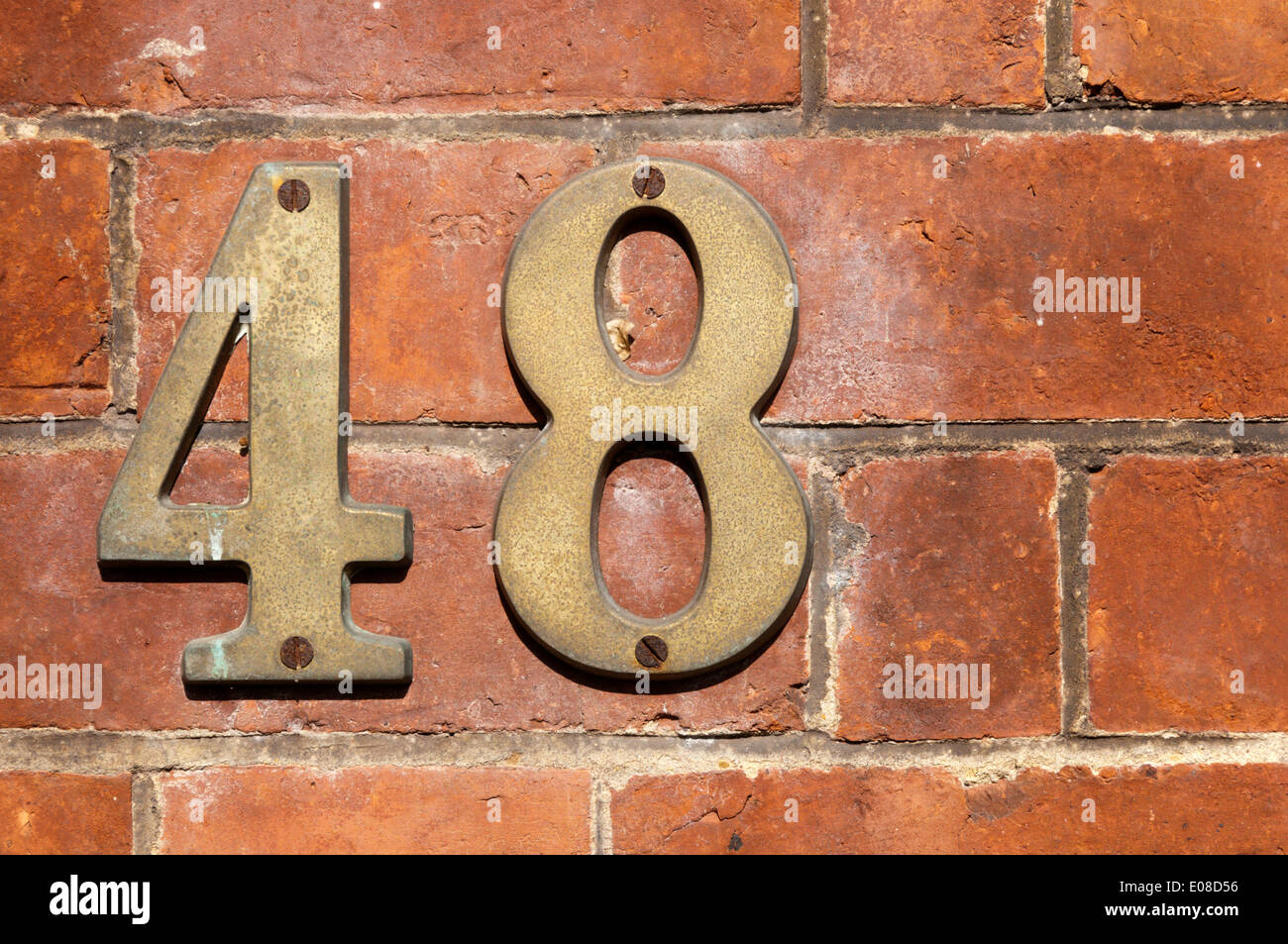 El número 48 de metal fijado a una pared de ladrillo. Foto de stock