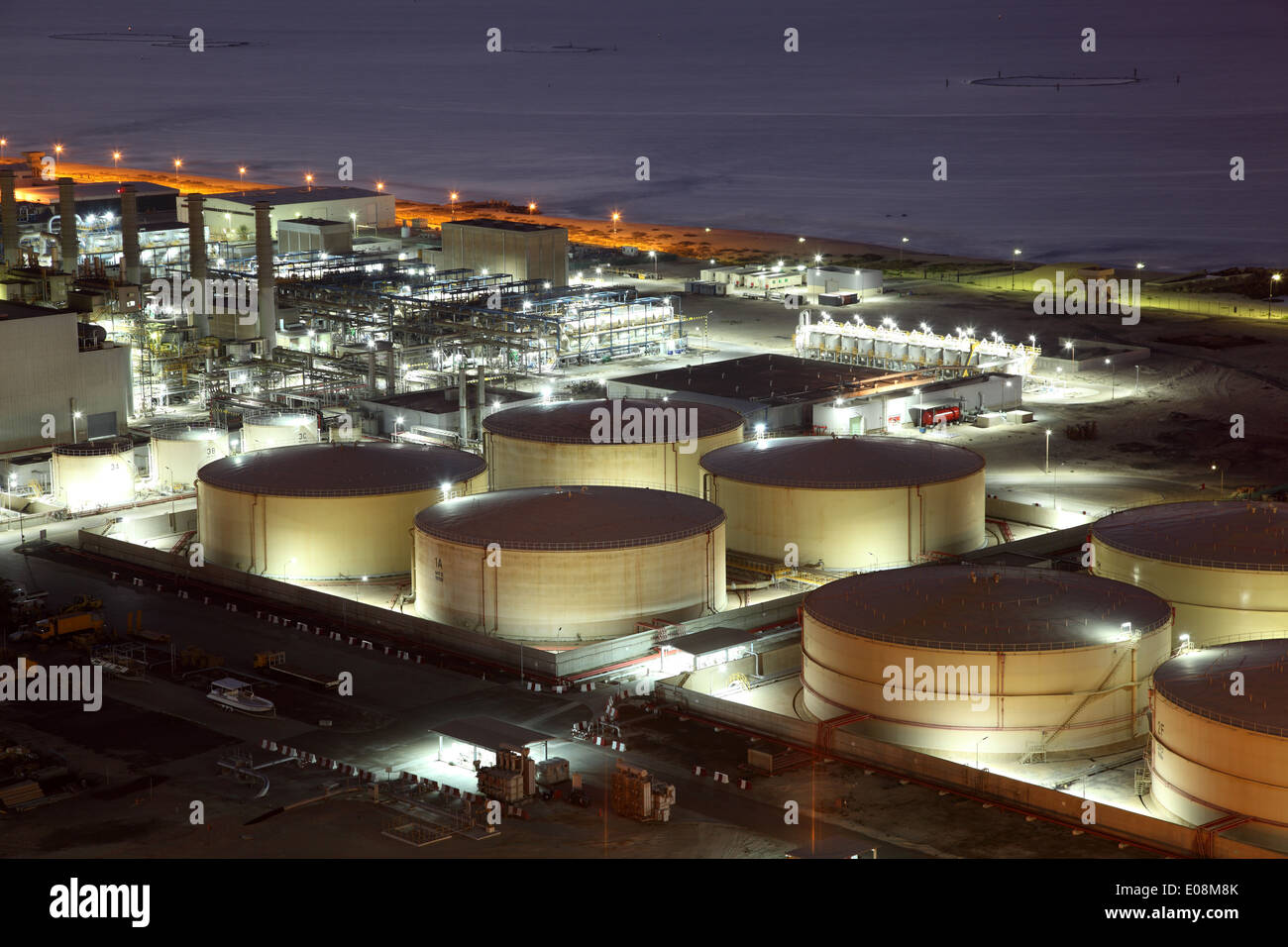 Tanques de almacenamiento de la refinería iluminada por la noche Foto de stock