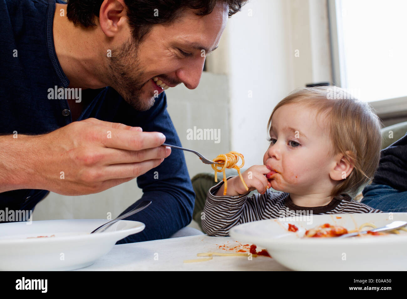 Padre de una hija de 1 año de alimentación espagueti Foto de stock