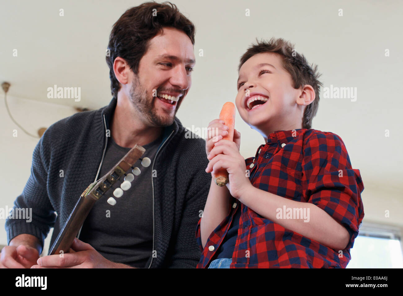 Padre e hijo con la guitarra y el micrófono de zanahoria Foto de stock