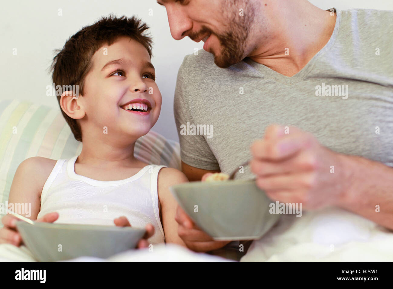 Padre e hijo desayunando en la cama Foto de stock