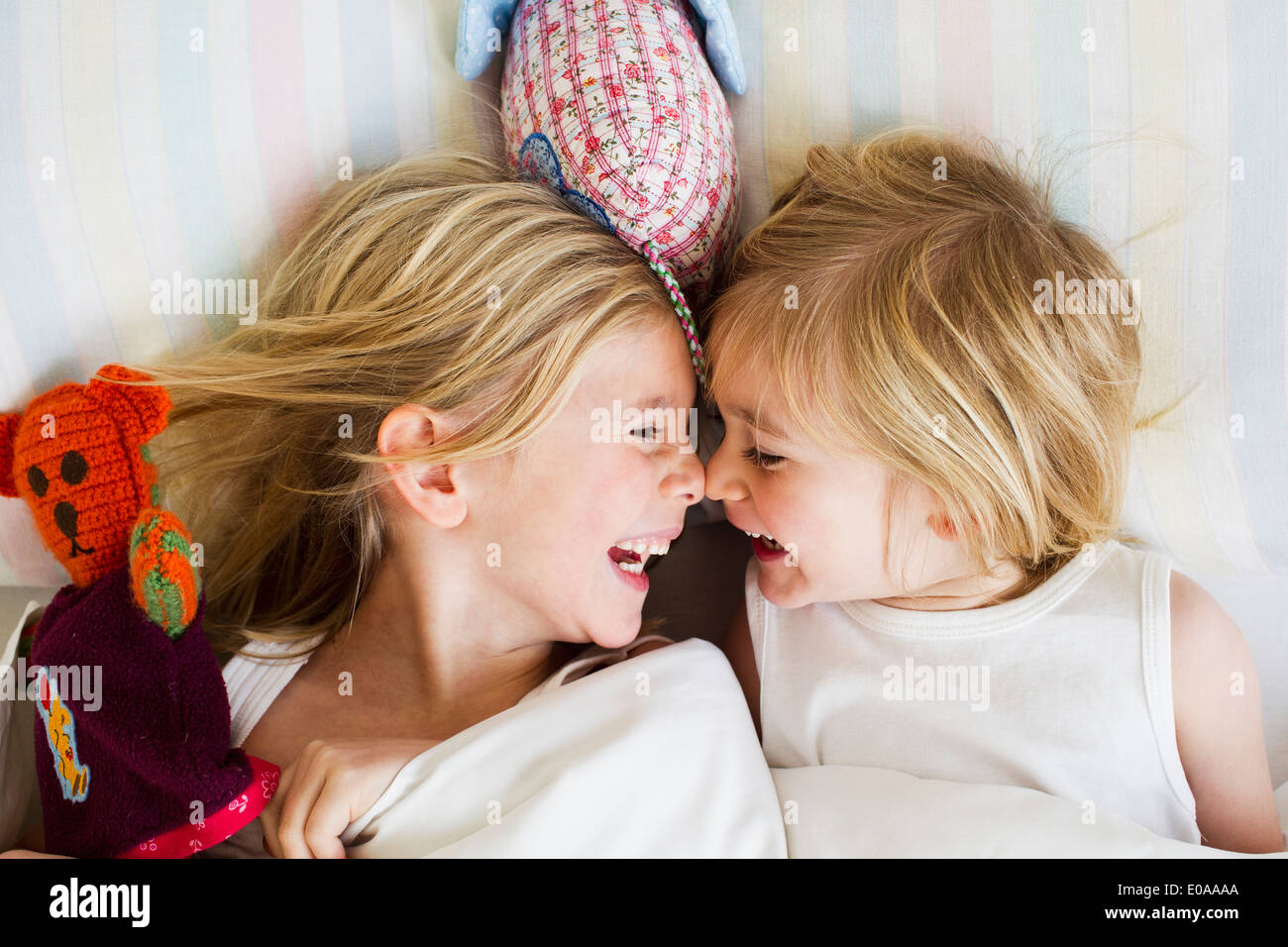 Retrato de dos jóvenes hermanas tumbado en la cama, cara a cara. Foto de stock