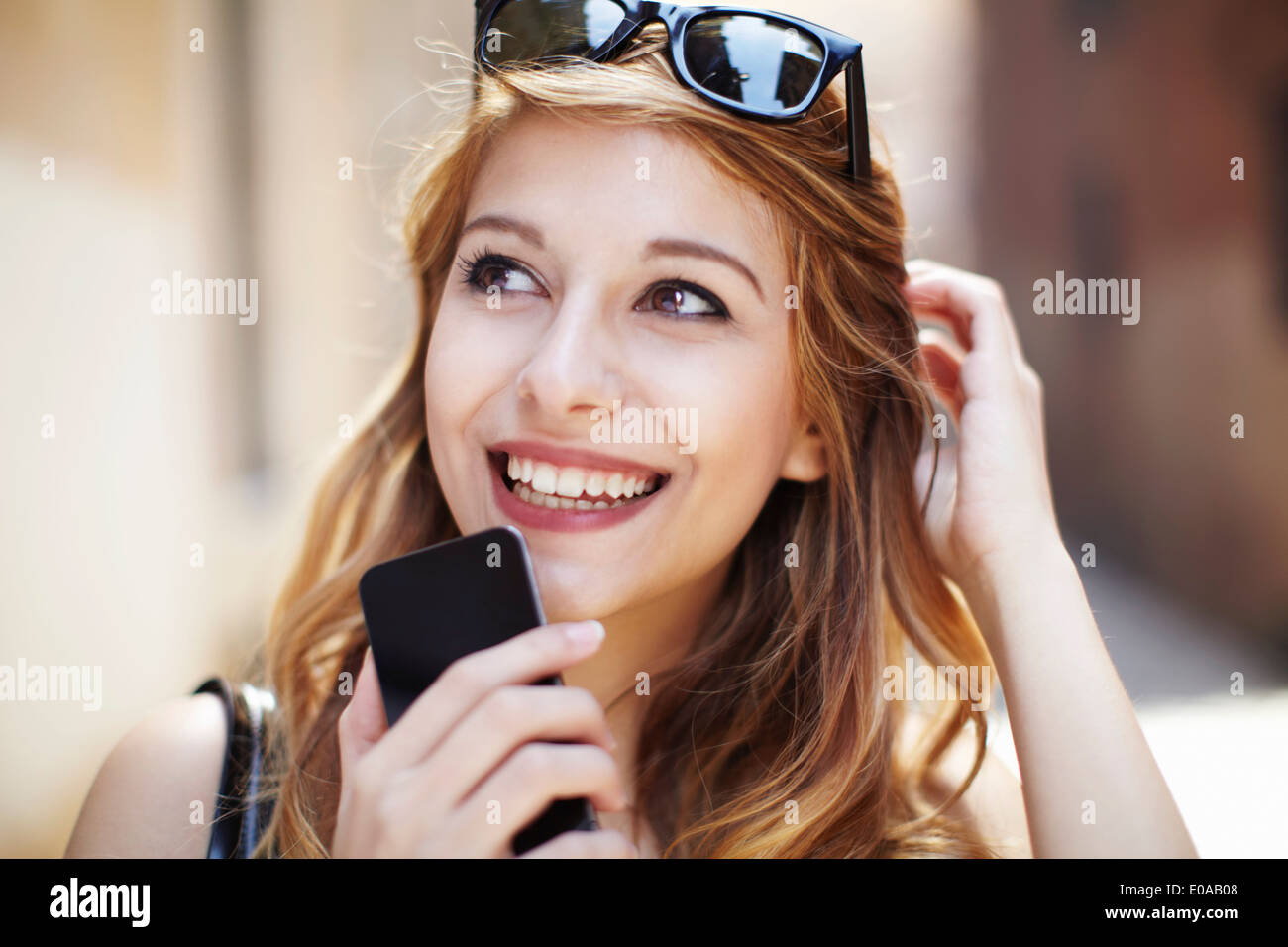 Sofisticada mujer joven con smartphone mirando hacia arriba Foto de stock