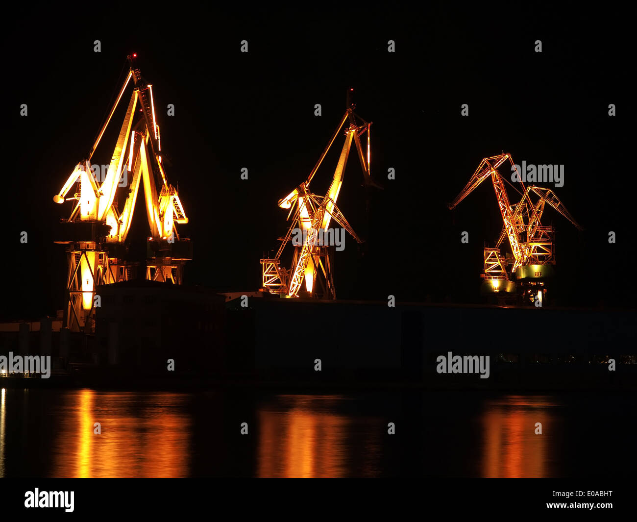 Grúas del astillero con reflejos, iluminación nocturna Foto de stock