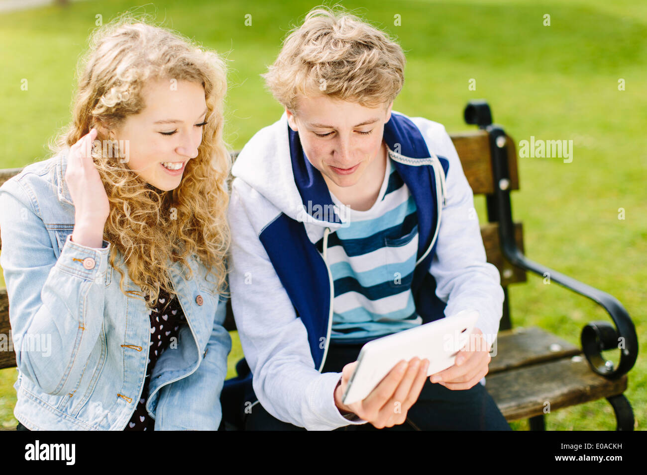 Hermanos adolescentes mirando tableta digital en un banco Foto de stock