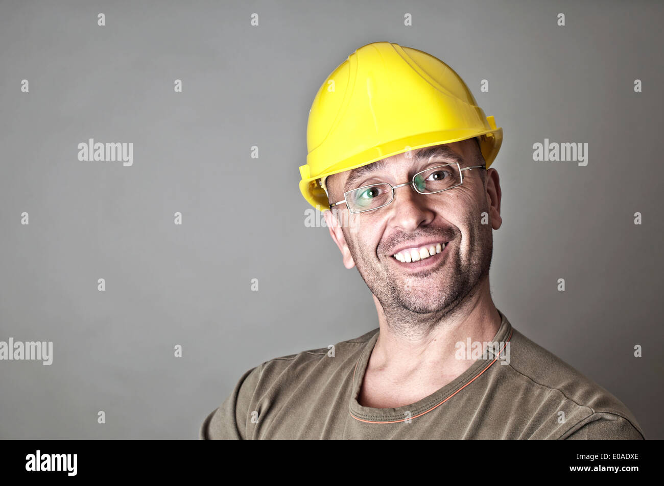Retrato de un amable trabajador sonriente con gafas y sombrero duro amarillo Foto de stock
