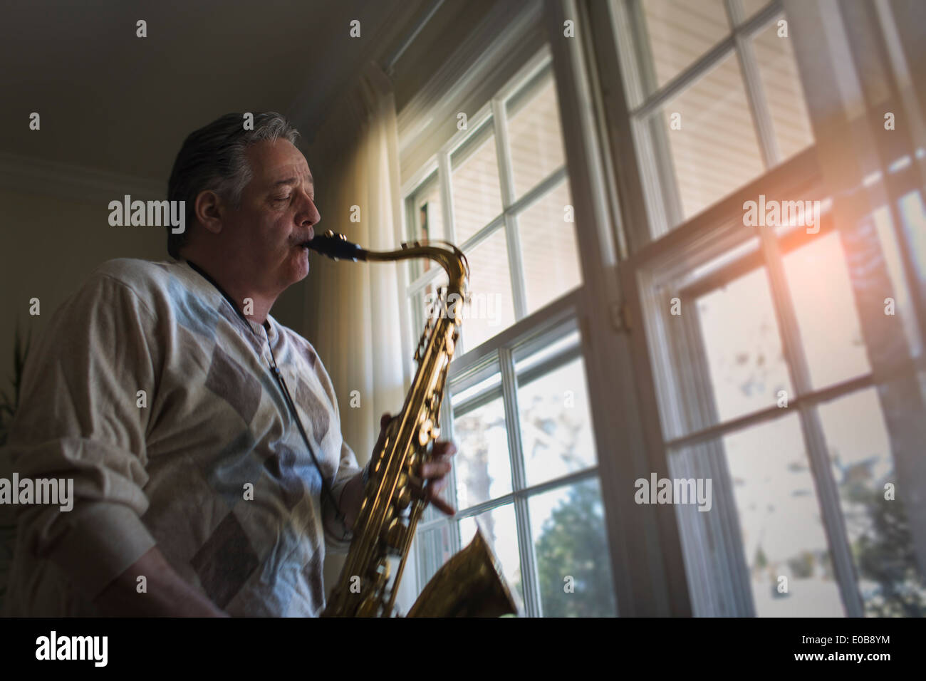 Hombre maduro en casa tocando el saxofón Foto de stock