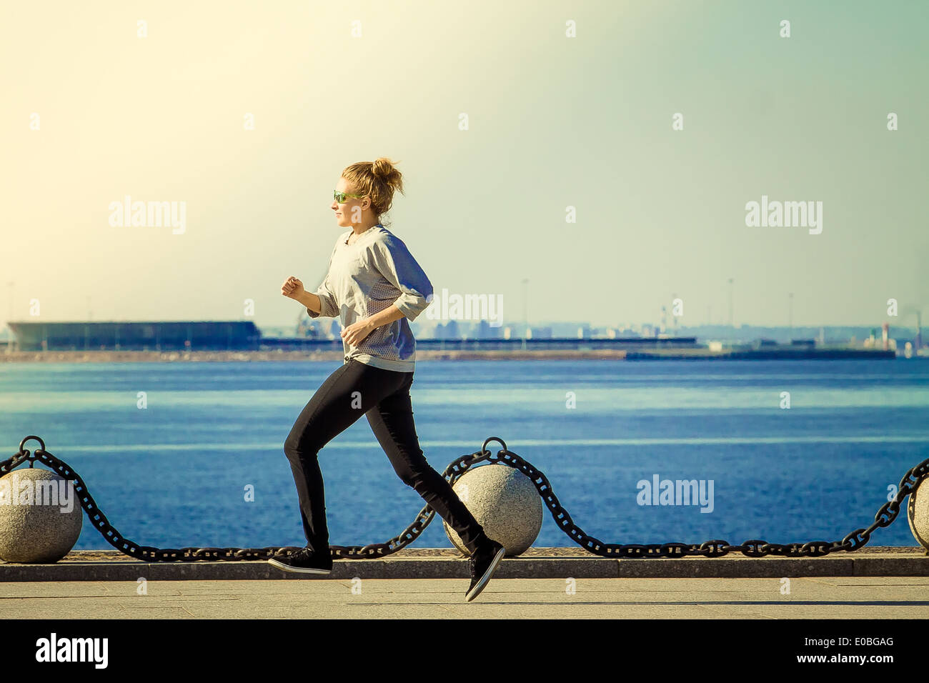 Mujer joven hace correr por la mañana en una orilla del golfo de Finlandia Foto de stock