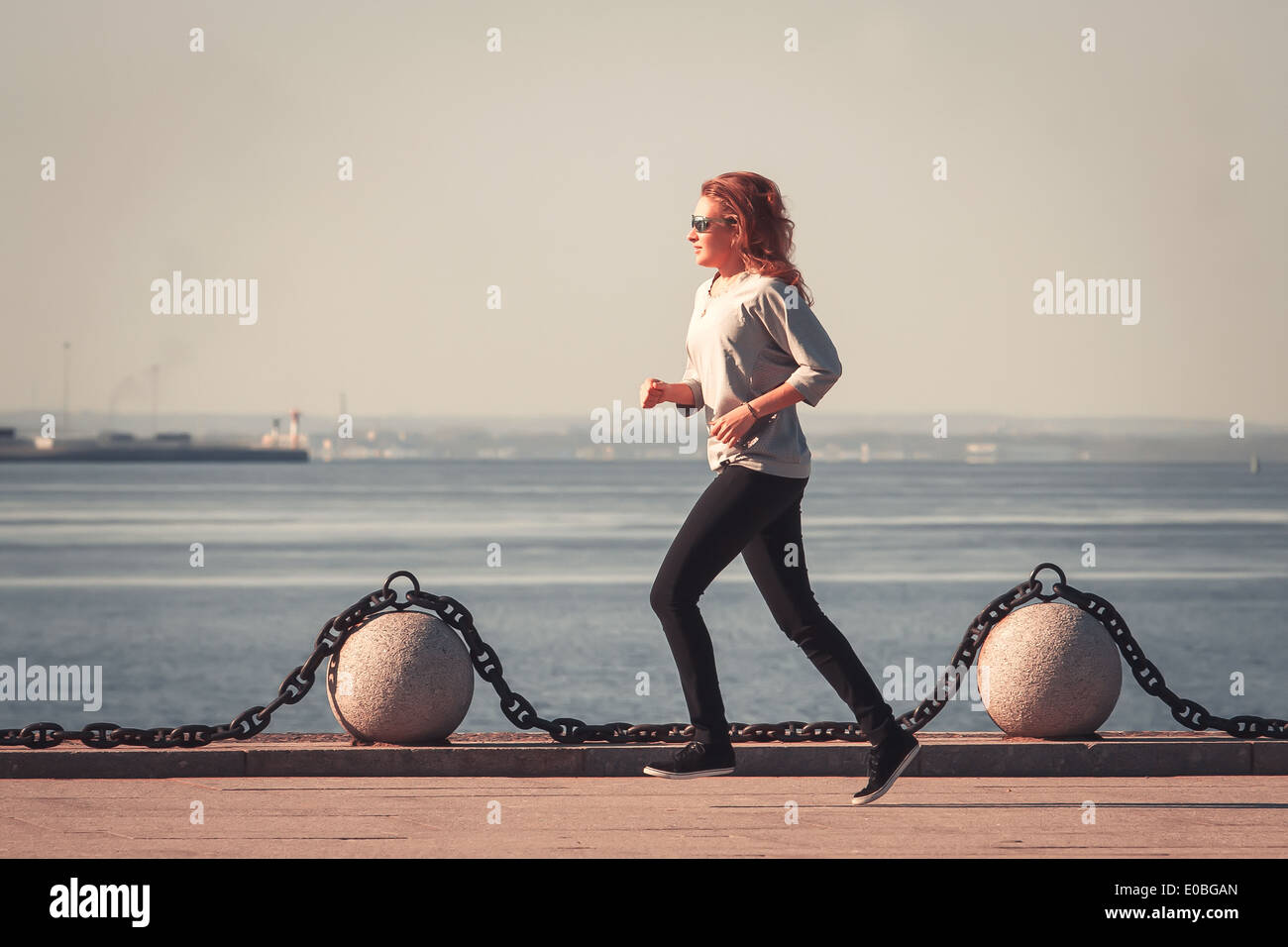 Mujer joven hace correr por la mañana en una orilla del golfo de Finlandia Foto de stock