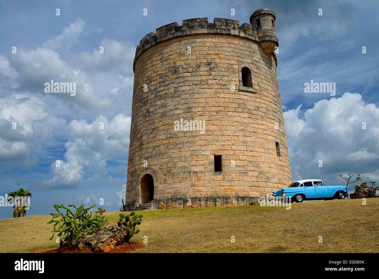 Castillo de Piedra atalaya ocultando una torre de agua en Varadero, en Cuba, con el clásico coche Chevy azul Foto de stock