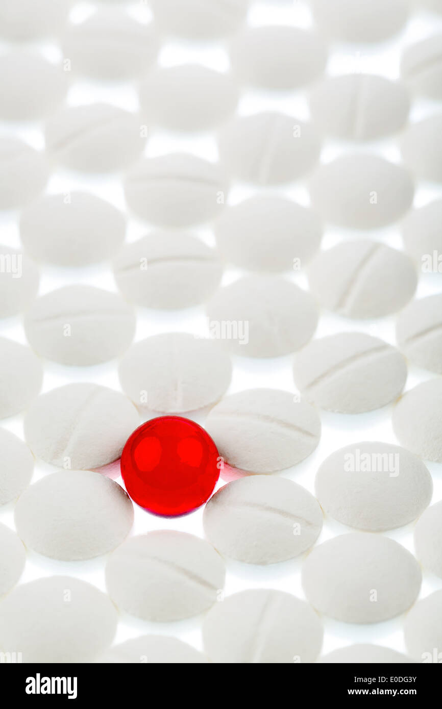 Tabletas blancas en contraste con una pastilla roja, simbólica foto del acoso y la individualidad, Weisse Tabletten im Kontrast m Foto de stock