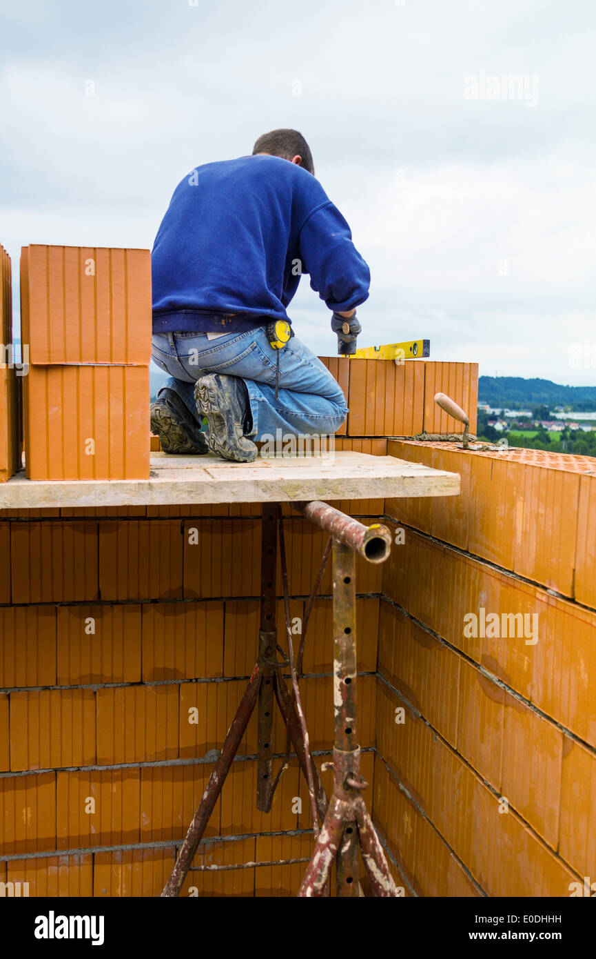 Anonymous, trabajador de la construcción en una obra con la construcción de una casa se establece por una pared de ladrillo. Pared de ladrillo de un mas Foto de stock