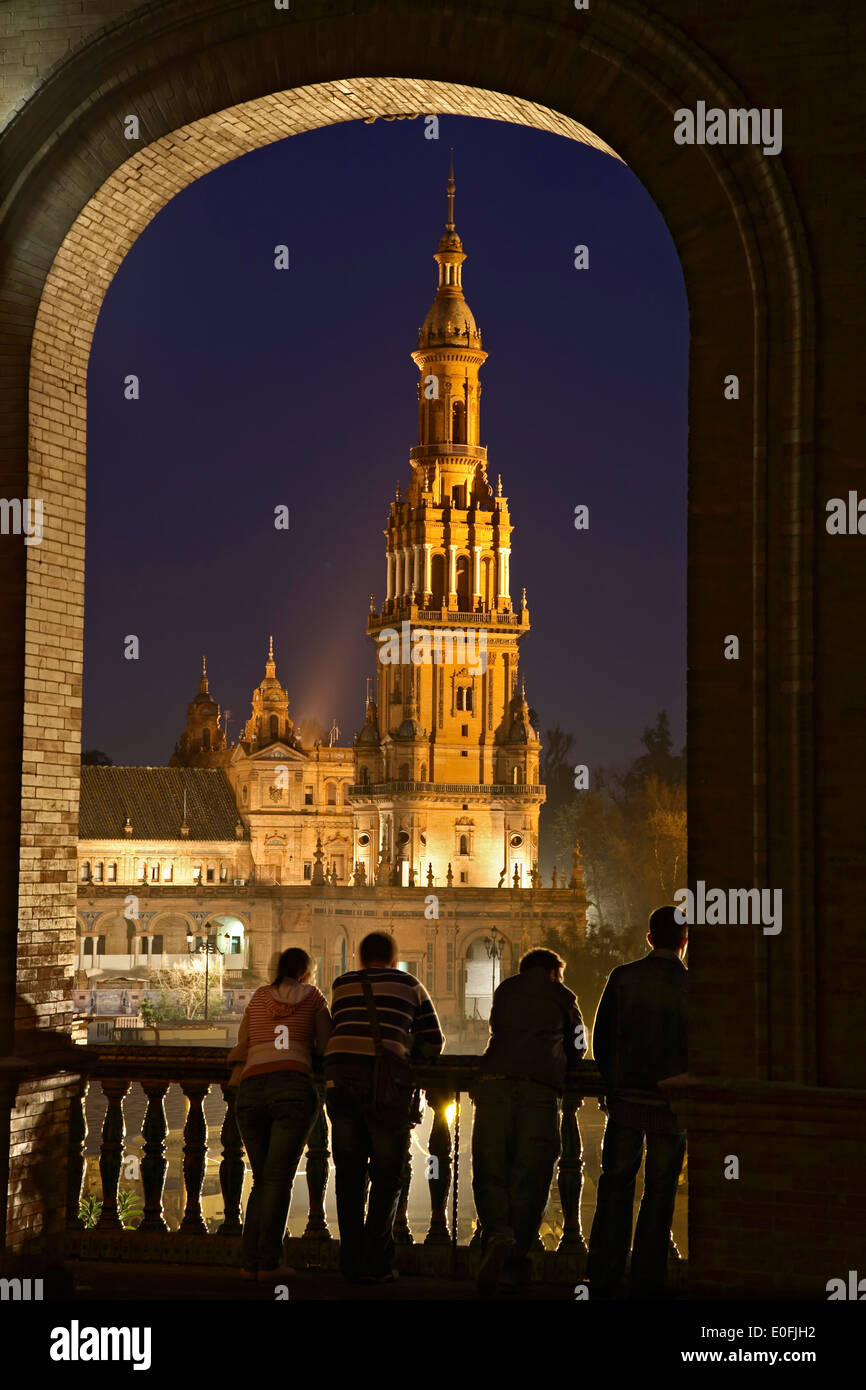 La gente admirando la torre a través de la ventana arqueada, Plaza de España, en la penumbra, Sevilla, España Foto de stock