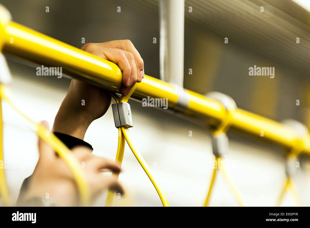 La mano de una persona sosteniendo una rampa en un concurrido tren de Metro de Londres. Foto de stock