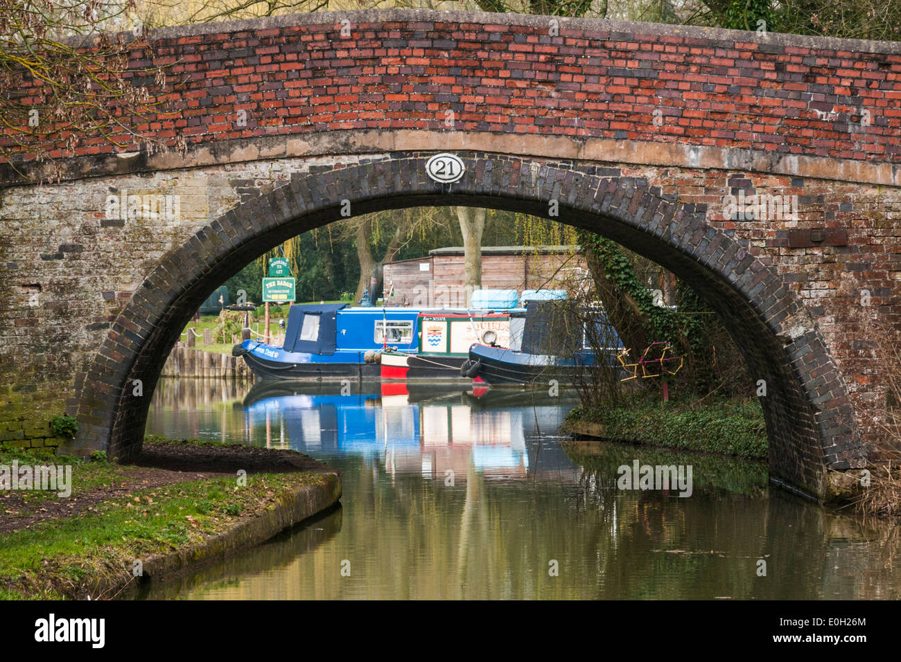 Mirando a lo largo de la Ashby canal a través del arco de un puente en estrechos botes en el otro lado Foto de stock