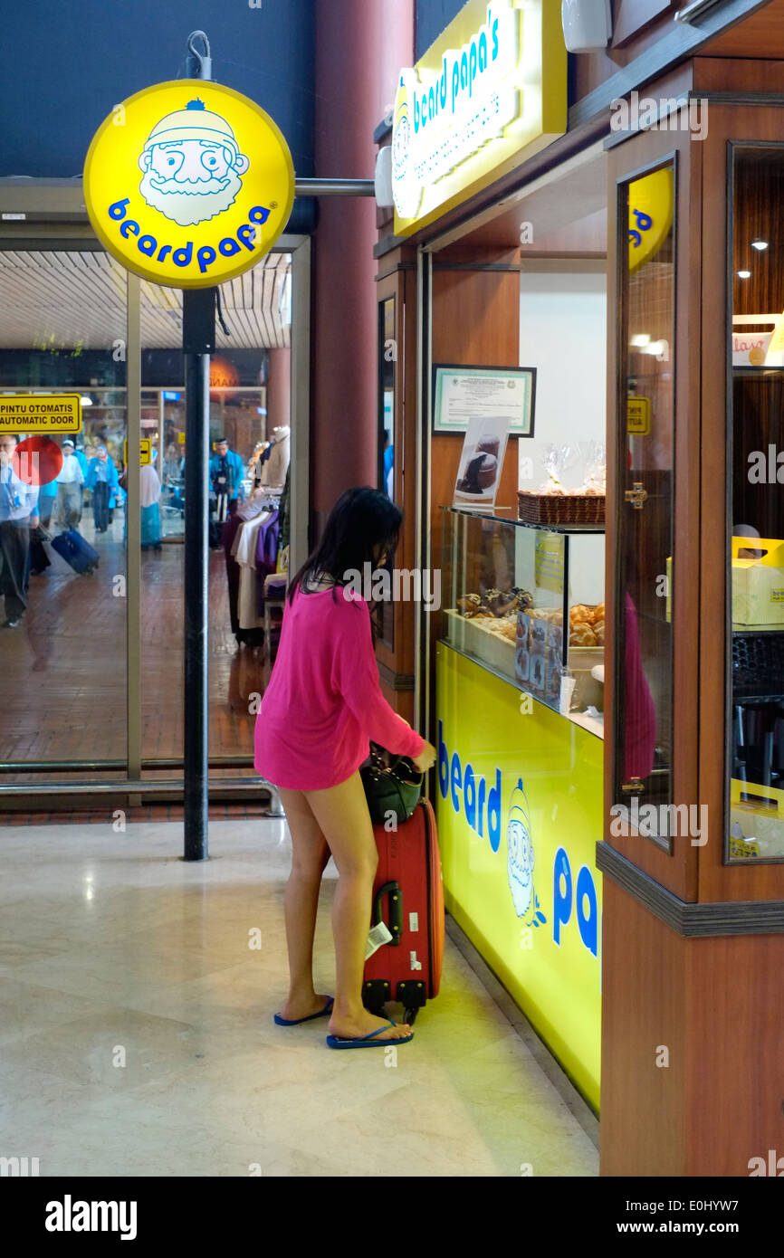 Mujer joven con traje extremadamente corto en busca de dinero en su bolso en el aeropuerto internacional de Soekarno Hatta jakarta indonesia Foto de stock