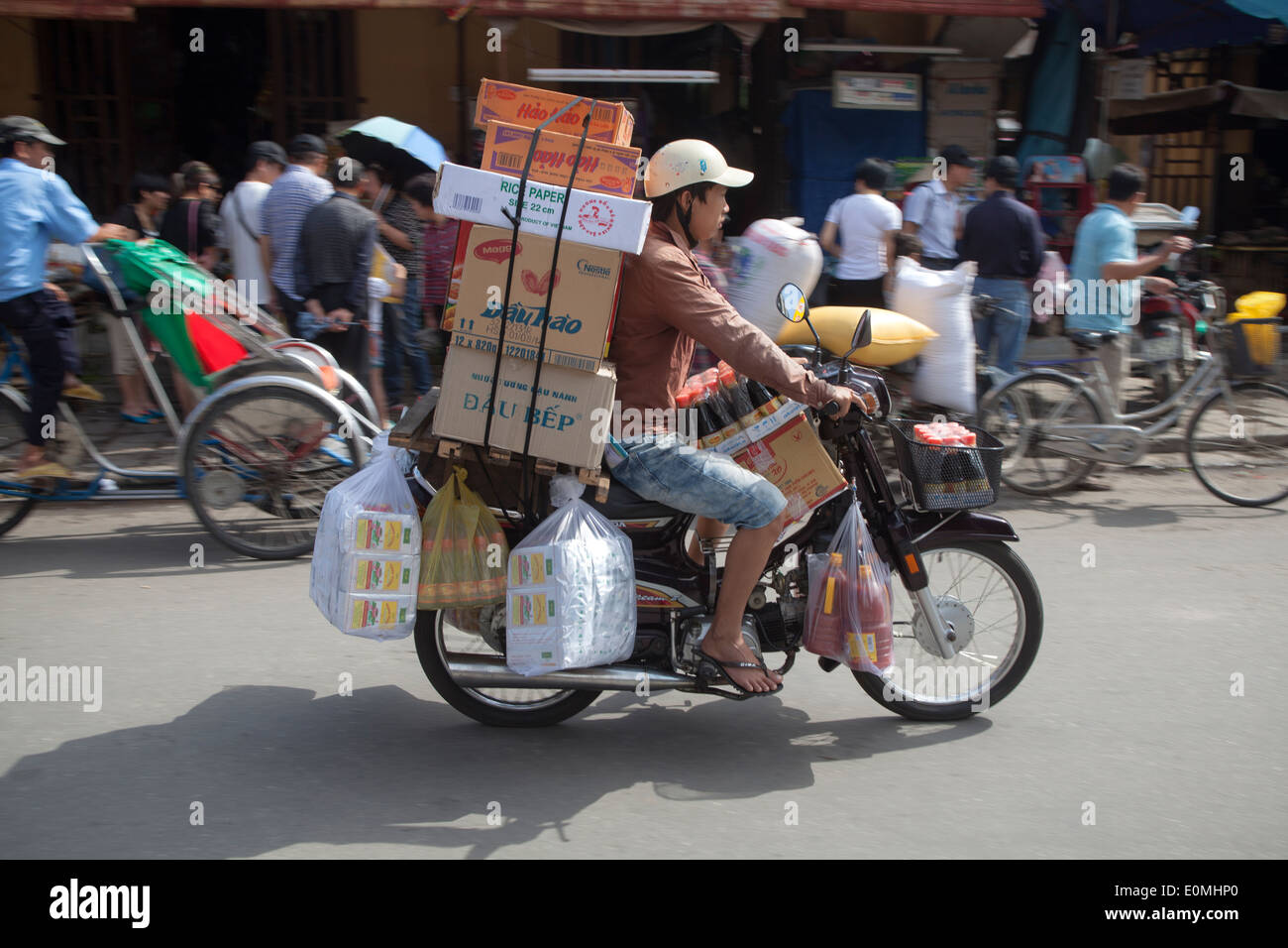El motorista cargado con paquetes en Hoi An Vietnam Foto de stock