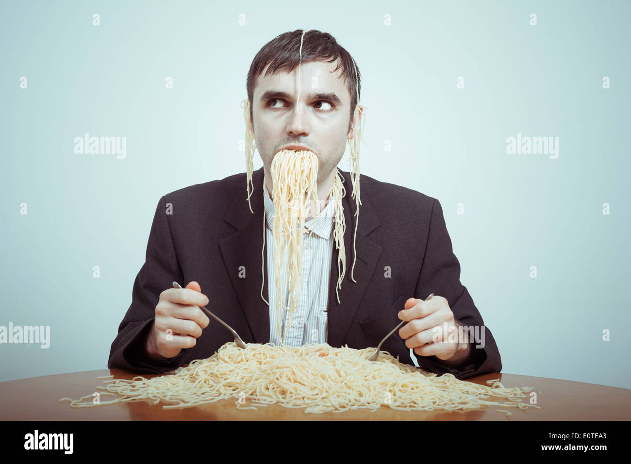 Comer en exceso y el consumismo concepto. Silly empresario desagradable comer pasta. Foto de stock