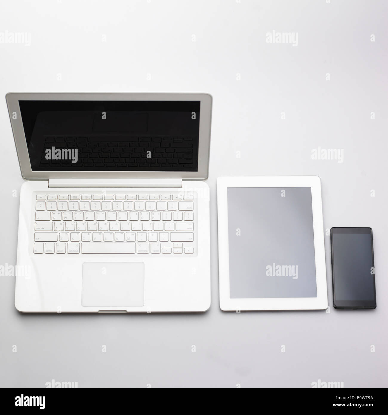 Un teléfono inteligente y un tablet junto a un ordenador portátil Foto de stock