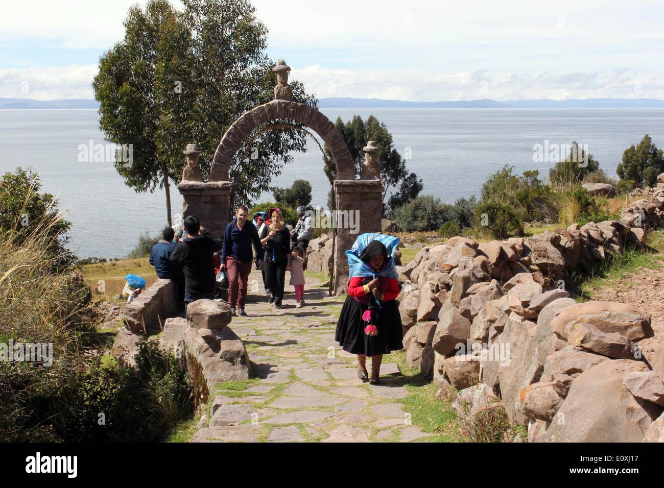 Puno, Perú. El 13 de mayo de 2014. Una mujer camina sobre una carretera en la isla flotante Taquile en el Lago Titicaca, en la región Puno, Perú, 13 de mayo de 2014. El Lago Titicaca y sus islas flotantes en el Perú, la región Puno no sólo los atractivos naturales, sino también porque la cultura única del pueblo quechua de Juliaca que viven allí. El lago Titicaca se encuentra en la Meseta de Collao, con las islas de Luna, Taquile, Uros, Amantani y Suriqui en ella. © Luis Camacho/Xinhua/Alamy Live News Foto de stock