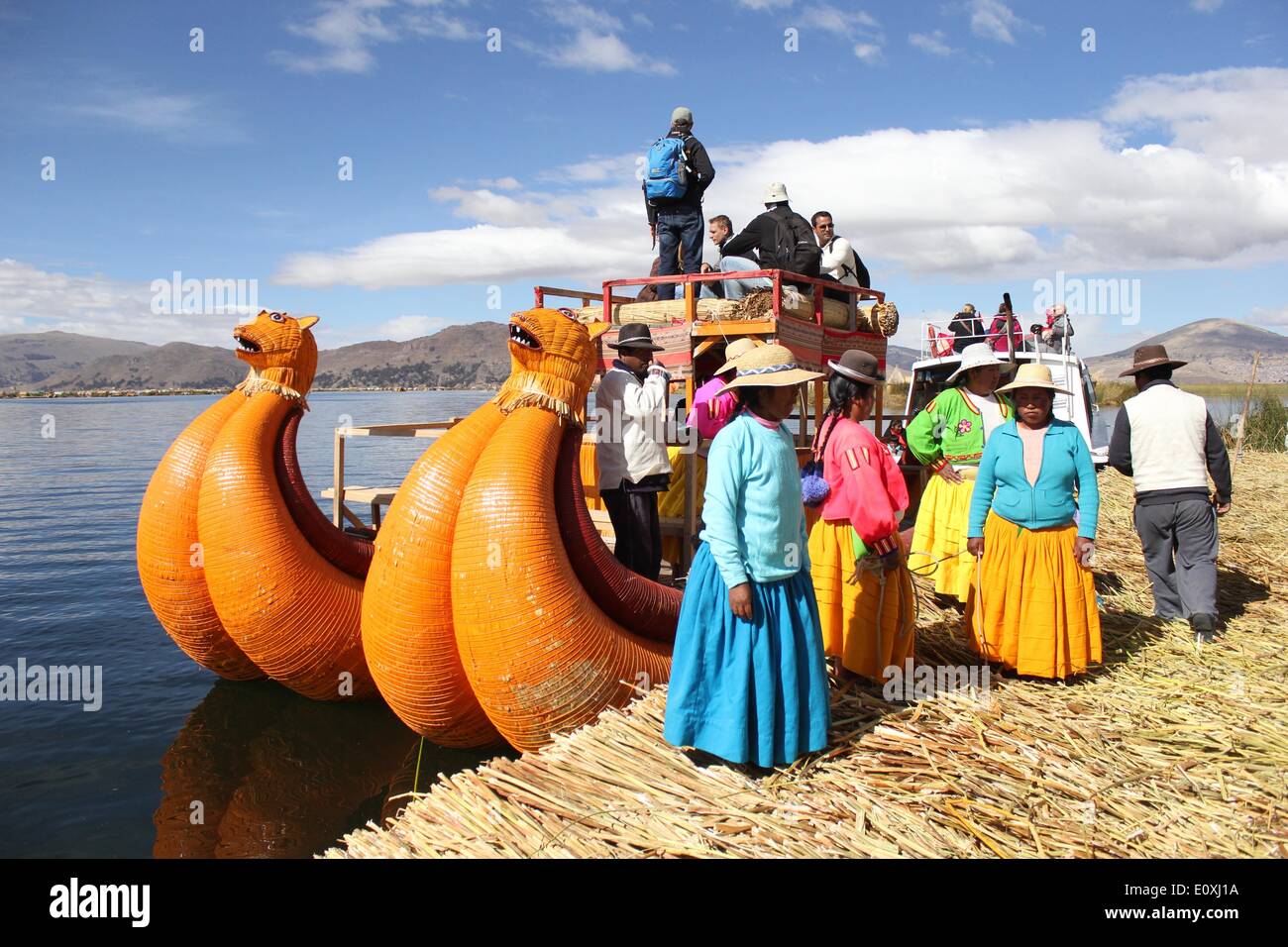 Puno, Perú. El 13 de mayo de 2014. Mujer de pie delante de un barco en la isla flotante de Los Uros en el Lago Titicaca, en la región Puno, Perú, 13 de mayo de 2014. El Lago Titicaca y sus islas flotantes en el Perú, la región Puno no sólo los atractivos naturales, sino también porque la cultura única del pueblo quechua de Juliaca que viven allí. El lago Titicaca se encuentra en la Meseta de Collao, con las islas de Luna, Taquile, Uros, Amantani y Suriqui en ella. © Luis Camacho/Xinhua/Alamy Live News Foto de stock