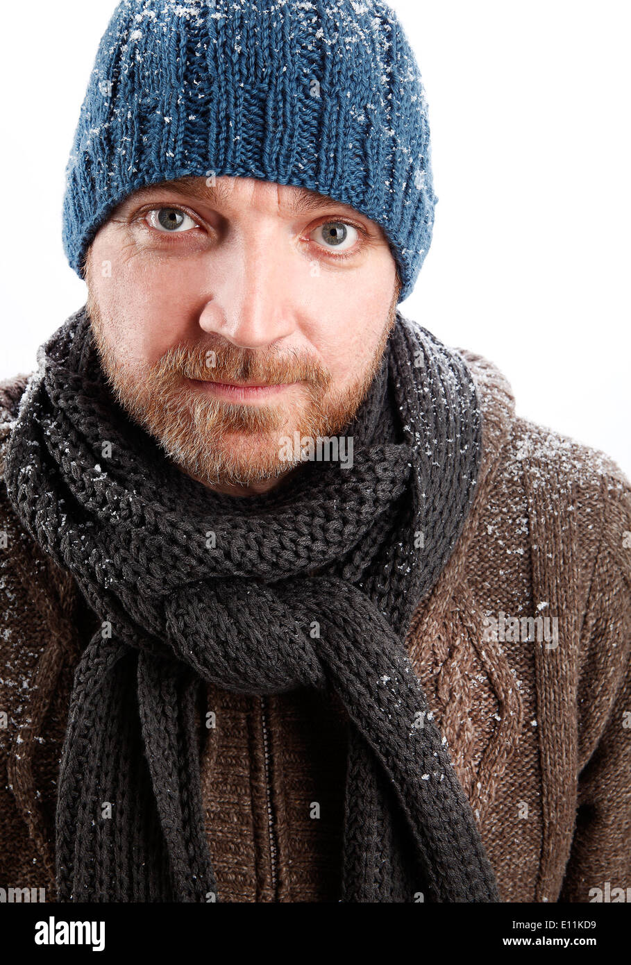 Retrato de un atractivo hombre con sombrero azul en la nieve. Foto de stock