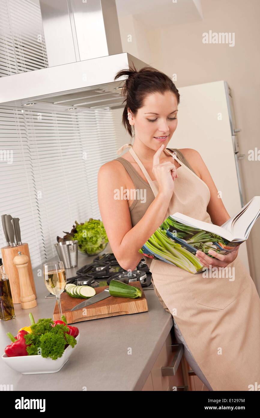 El 21 de octubre de 2009 - 21 de octubre de 2009 - El pelo castaño joven mujer leyendo el libro de recetas en la cocina C Foto de stock