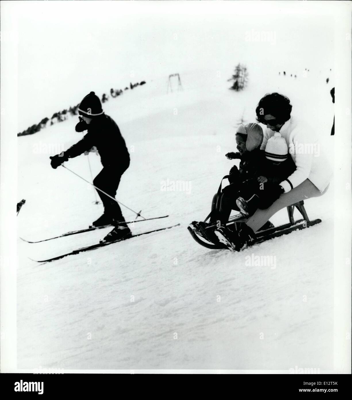 El 25 de febrero, 2012 - Swiss diversión para toda la familia: el niño está mejorando su esquí en un principiante la madre lleva a su pendiente, mientras que otros dos jóvenes en un tobagganing paseo por la misma colina pequeña en un resort en Suiza. Foto de stock