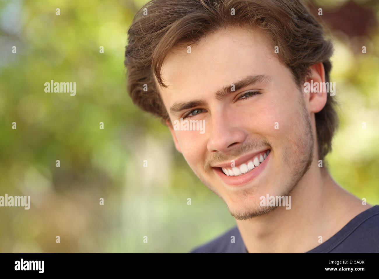 Hombre hermoso rostro con una sonrisa perfecta, blanca con un fondo verde Foto de stock