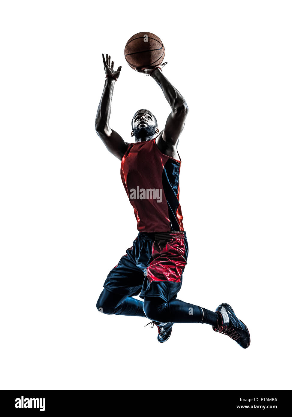 Un hombre africano jugador de baloncesto saltando lanzando en silueta aislado fondo blanco. Foto de stock