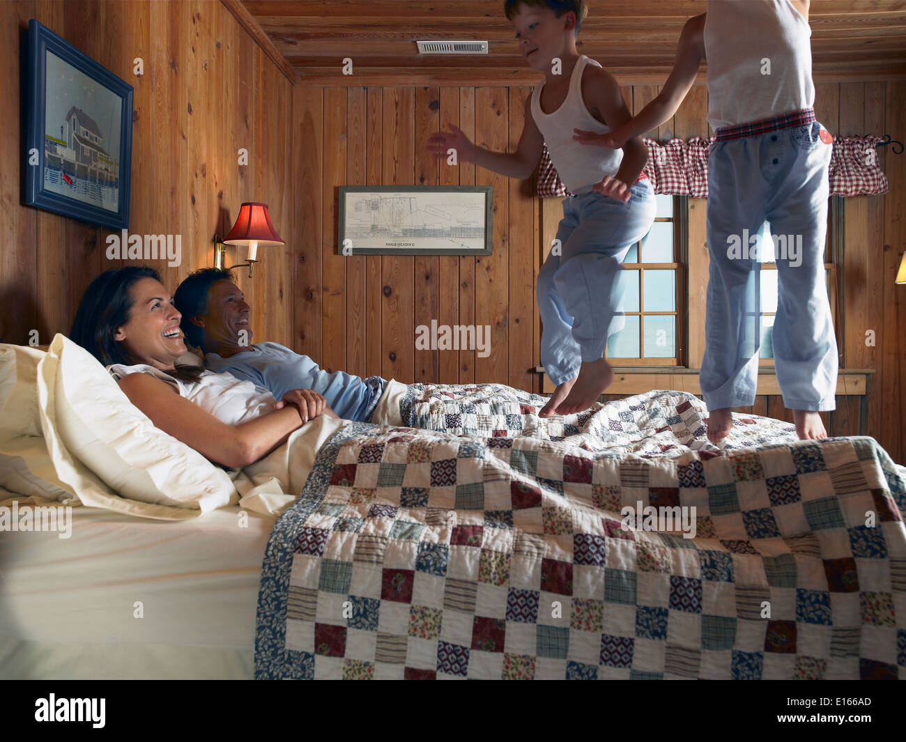 Los muchachos saltar en la cama de los padres. Foto de stock