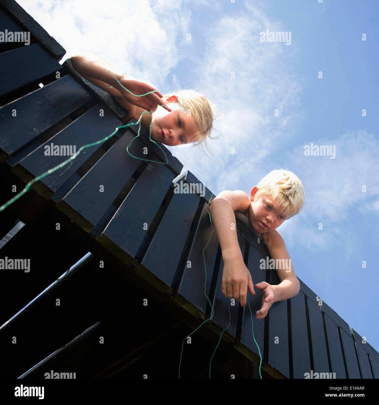 Dos niños de pesca desde el puente mediante cadena Foto de stock