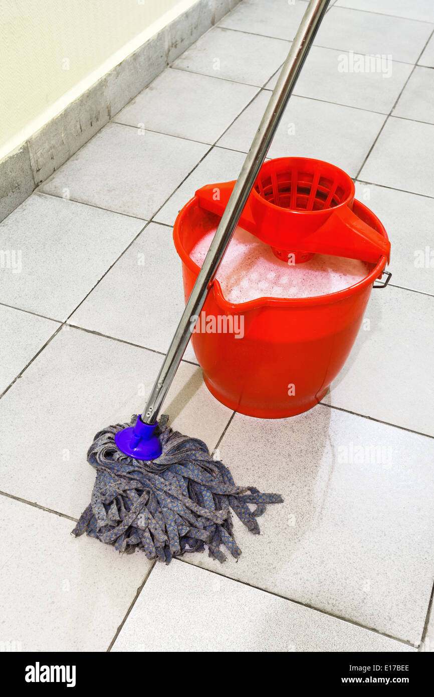 Rojo balde con agua de lavado y trapear los pisos de azulejo Fotografía de  stock - Alamy