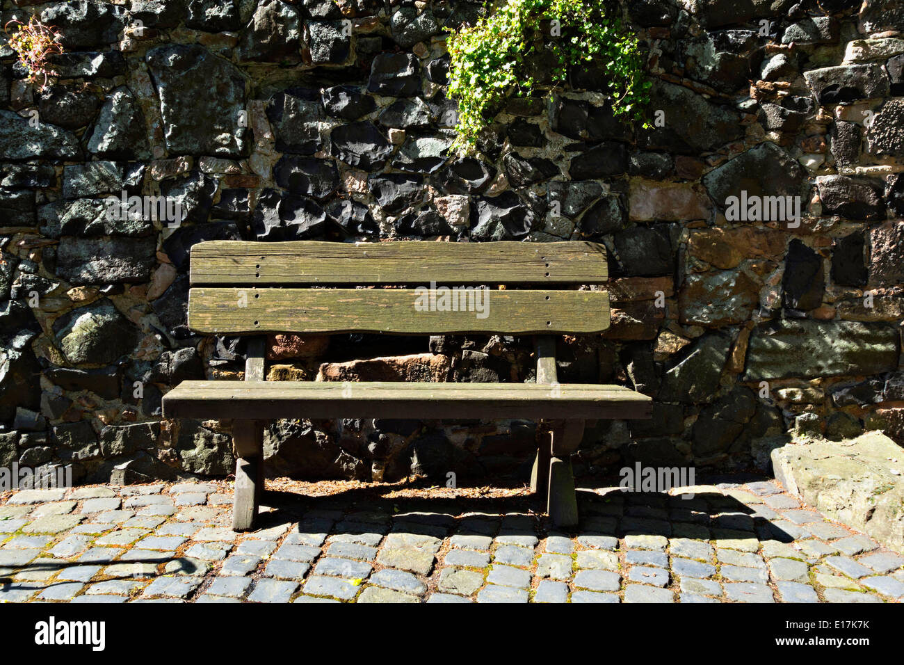 Banqueta de madera vieja contra la pared de piedra, en Alemania, en Europa. Foto de stock