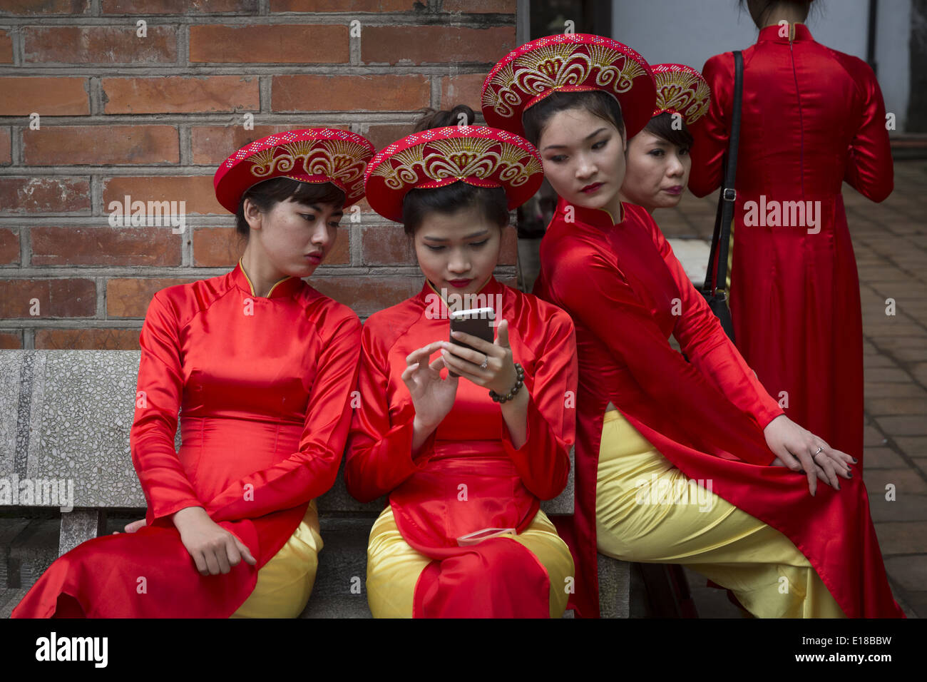 Un grupo de mujeres vestidas en trajes tradicionales, mirando el teléfono de uno de ellos. Foto de stock