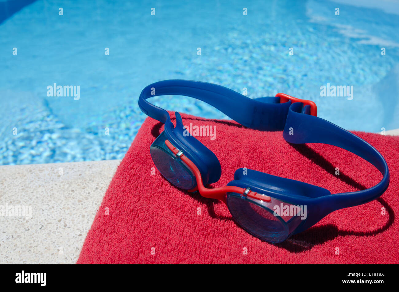 Gafas de natación y toalla colocadas en el puente de salida junto a la  piscina.