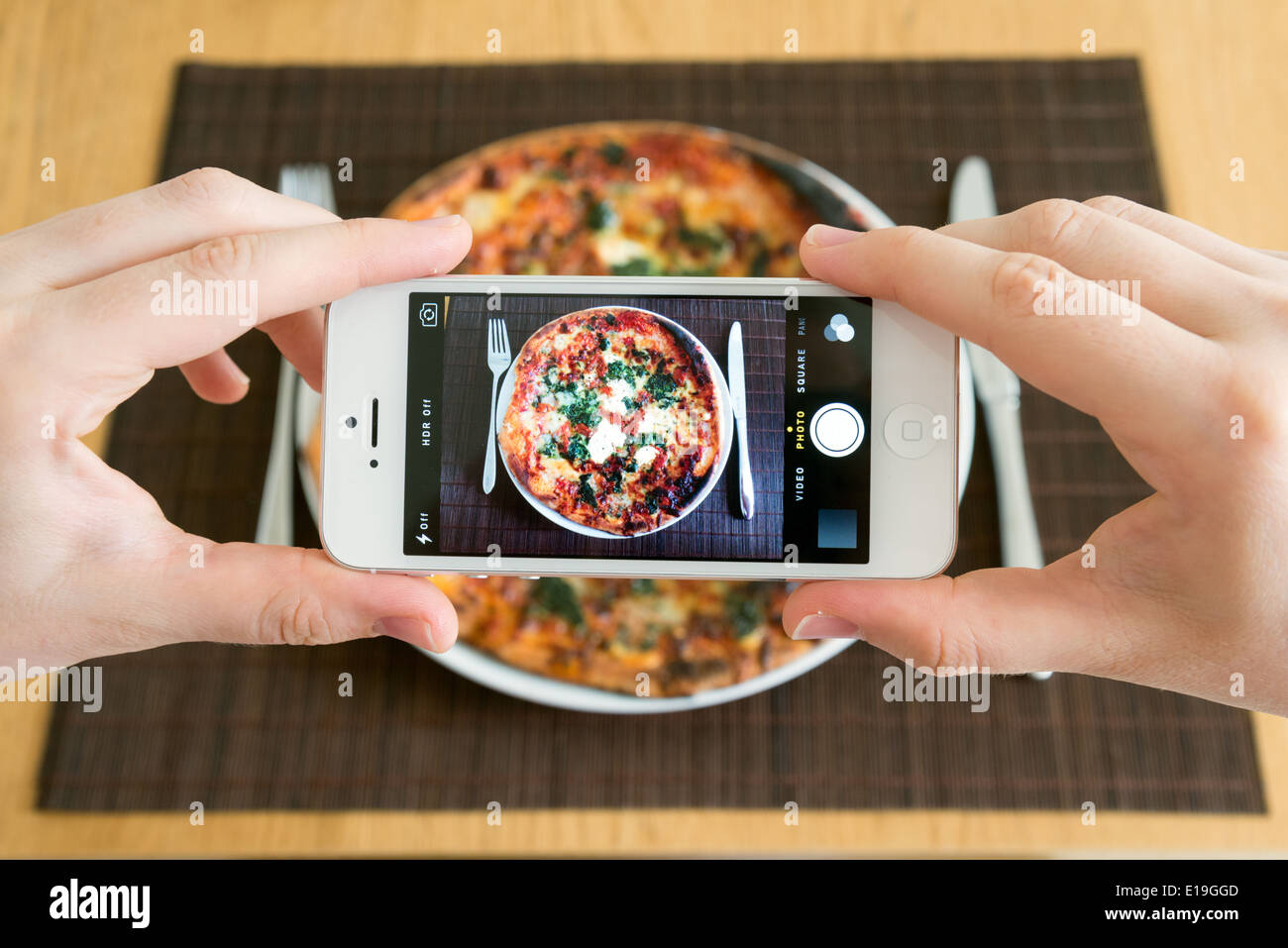 Tomar una foto de la comida de la pizza con la cámara blanca del teléfono inteligente del iPhone Foto de stock