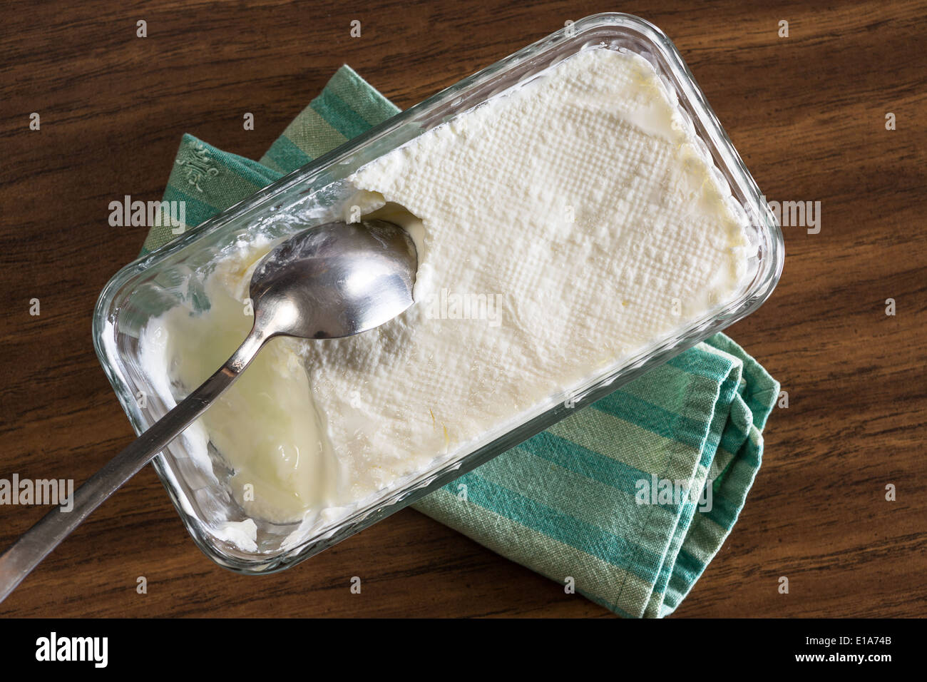 Yogur casero listo para servir en una tela a rayas verde sobre la mesa con una cuchara dentro Foto de stock