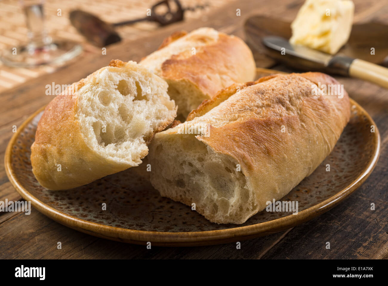 Pan francés baguette y mantequilla sobre una mesa de madera rústica. Foto de stock