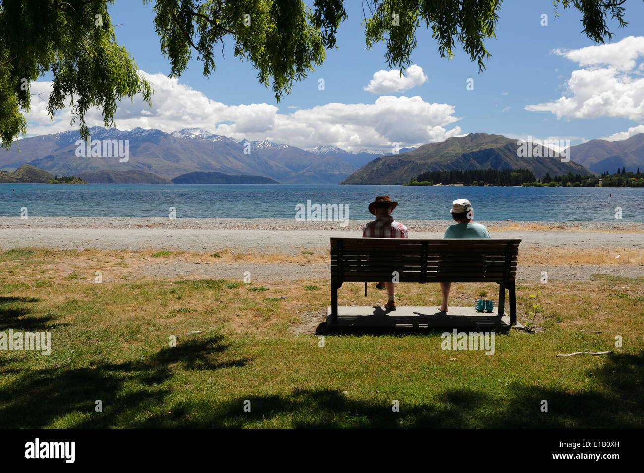 Par sentado en la banqueta junto al lago, el Lago Wanaka, Wanaka, Otago, Isla del Sur, Nueva Zelanda, Pacífico Sur Foto de stock
